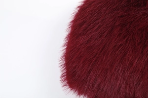 Gros plan sur la garniture en fausse fourrure bordeaux avec une texture douce et dense