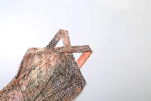 Dettaglio del tessuto con stampa serpente rosa e design incrociato del collo a lupetto