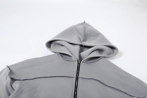 Detailansicht grauer Kapuzenpullover mit sichtbaren Nähten und hochwertigem Metallreißverschluss