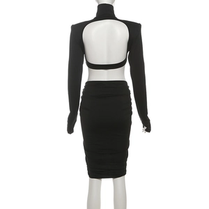 Détail d'une robe noire dos nu à manches longues avec texture froncée et passe-pouces