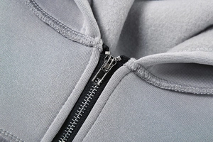 Detailaufnahme des schwarzen Reißverschlusses und grauen Fleece-Futters der Kapuzenjacke