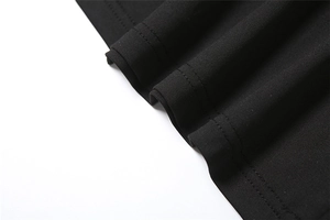 Detailed close-up of precise stitching and soft knit fabric on the black dress hemline
