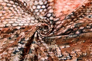 Dettaglio del tessuto con stampa a serpente e consistenza setosa con eleganti pieghe a spirale