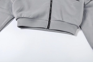 Detail von grauem Hoodie-Saum mit schwarzem Metallreißverschluss und Doppelnähten