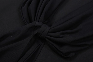 Detail of elegant black mesh fabric featuring a sophisticated twist knot design on the dress