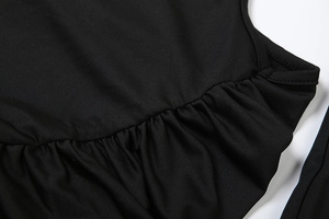 Détail macro du tissu noir froncé avec des plis fins sur la manche d'une mini robe