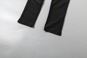 Détail de l'ourlet de la combinaison noire avec coutures fines et tissu synthétique soyeux
