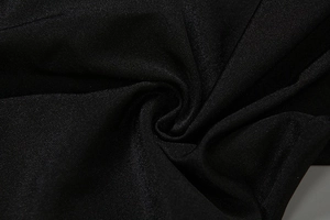 Détail macro du tissu sergé noir avec un éclat subtil et un drapé élégant de haute qualité