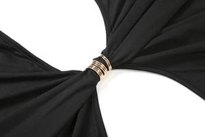 Détail d'une robe noire moulante avec taille découpée et anneaux métalliques dorés