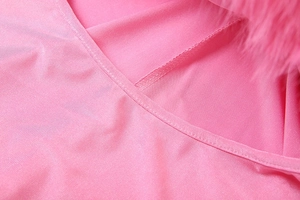 Détail du tissu soyeux rose avec double couture précise et bordure de col en fausse fourrure