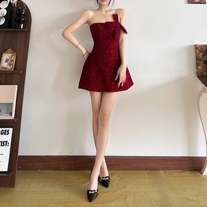 Détail d'une mini robe bordeaux à paillettes avec un gros nœud sur l'épaule