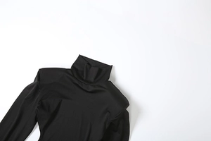 Détail d'un haut noir à col montant avec épaulettes et tissu élastique à effet brillant