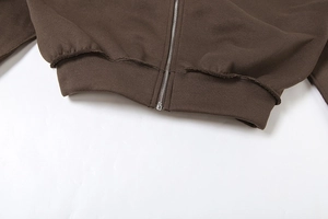 Detail eines braunen Zip-Hoodies mit geripptem Saum mit offener Kante und Metallreißverschluss