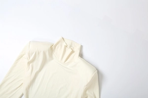 Gros plan sur le col haut élégant et la texture en maille douce d'une robe couleur crème