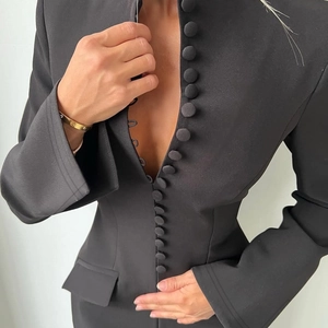 Detail eines schwarzen taillierten Blazers mit stoffbezogenen Knöpfen und Taillendesign