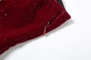 Détail d'une robe en velours rouge avec fermeture éclair invisible et paillettes