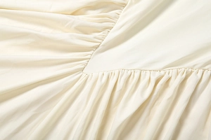 Vue détaillée du drapé et de la couture en V sur cette robe dos nu de couleur beige