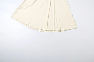 Gros plan détaillé de l'ourlet lisse et du tissu de qualité sur cette robe longue blanc cassé