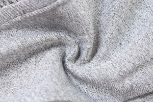 Close-up detail of grey knitted fabric texture showing fine stitching and soft cotton blend fibers