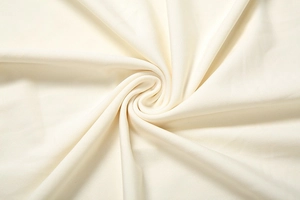 Gros plan sur la texture du tissu en maille crème avec un drapé doux et des détails fins
