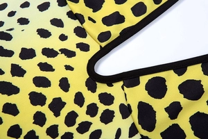 Detail of yellow leopard print fabric with neat black edge binding and smooth texture