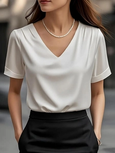 Close-up of white satin V-neck blouse featuring elegant shoulder pleats and folded cuffs