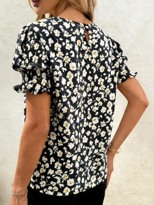 Détail des manches bouffantes fleuries avec bords volantés et fermeture boutonnée au dos