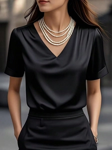 Detail of elegant black satin short-sleeved V-neck top featuring smooth glossy fabric texture