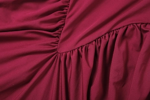 Détail macro du tissu rouge vin avec texture froncée et fine couture en forme de V