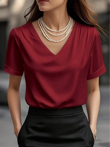 Detail of burgundy V-neck satin blouse featuring elegant shoulder pleats and smooth texture