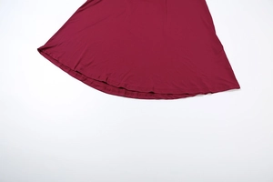 Détail de l'ourlet évasé de la robe longue rouge bordeaux avec double couture de qualité