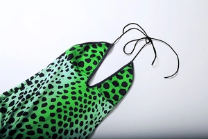 Detail of the plunging V-neck and black tie straps on green leopard print dress