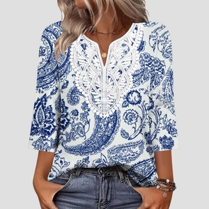 Dettaglio dello scollo a V in pizzo e stampa paisley blu su camicetta bianca larga