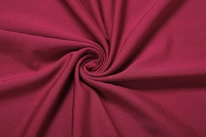 Détail macro du tissu en maille rouge vin montrant la douceur et le drapé chic