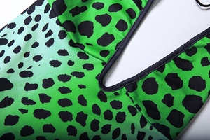 Detailed view of deep V-neckline with black piping and green leopard print fabric