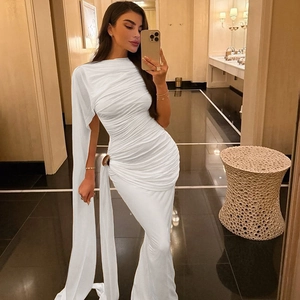 Détails de la robe drapée blanche avec boucle métallique et cape élégante sur l'épaule