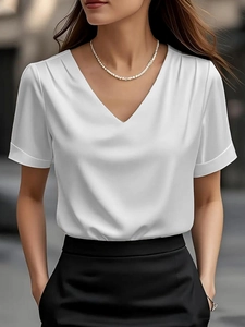 Close-up of white satin V-neck blouse showing silk texture and shoulder pleat details