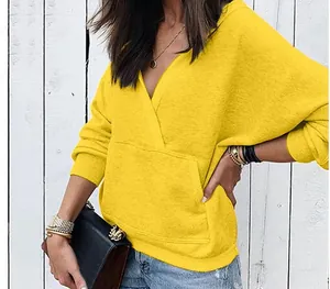 Macro view of bright yellow hoodie with crossover V-neck and kangaroo pocket detail