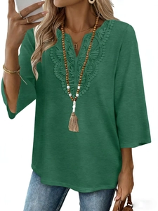 Detail of dark green V-neck blouse with intricate lace embroidery and three-quarter sleeves