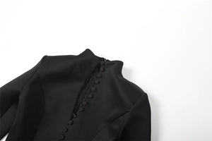 Detail eines schwarzen Stehkragenkleids mit eleganten stoffbezogenen Knöpfen auf Webstoff