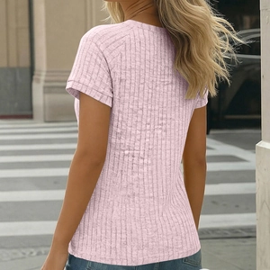 Outdoor street view of the back of a pink ribbed knit short sleeve T-shirt with denim jeans