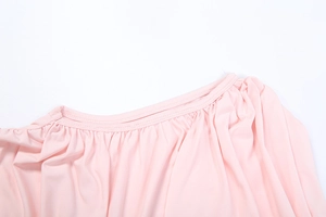 Détail de l'encolure d'une robe rose élégante avec une texture plissée et tissu fluide