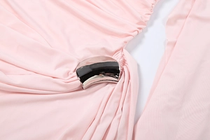 Détail d'une robe rose clair avec drapé latéral élégant et boucle en métal argenté