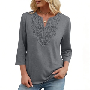 Close-up of the elegant V-neckline with delicate floral lace embroidery on a grey tunic