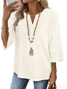 Close-up of white V-neck top with intricate lace crochet embroidery and boho tassel necklace