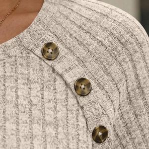 Detail shot of light grey ribbed knit shirt with round neck and three tortoiseshell buttons