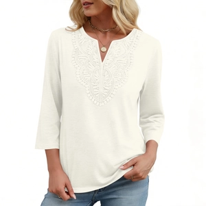 Detail of delicate white lace embroidery on V-neck cotton top with three-quarter sleeves
