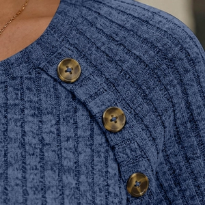 Detailed close-up of ribbed navy blue knit fabric with large tortoise shell buttons