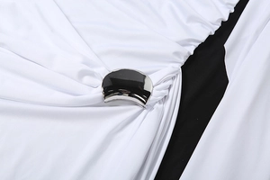 Détail de robe blanche avec liseré noir et boucle métallique créant des plis élégants