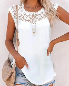 Detail of white sleeveless top featuring intricate floral lace patchwork and crochet neck